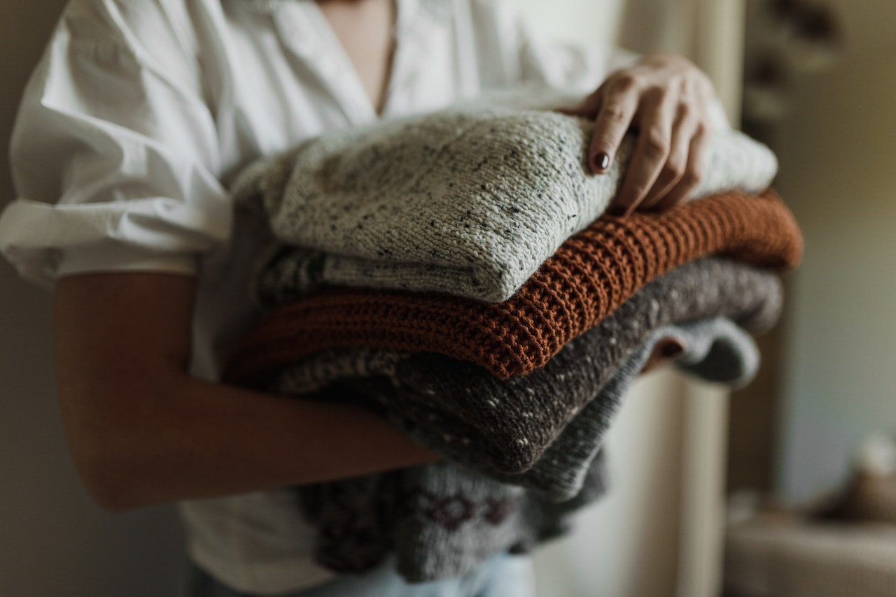 a photo of a woman holding winter sweaters 
