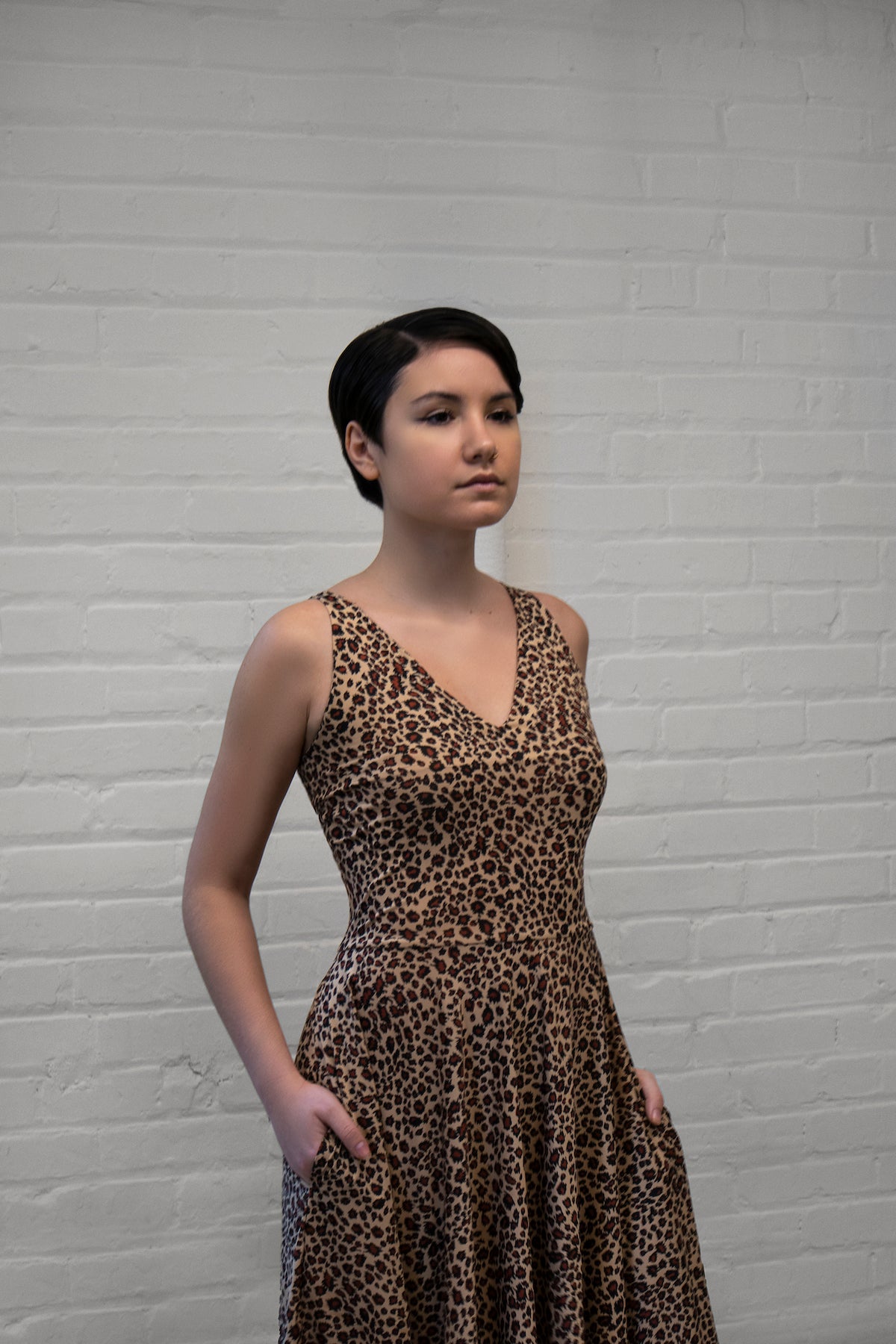 a model wearing a leopard animal print dress with a v-neck and no sleeves